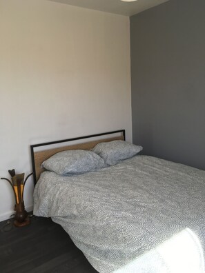 Et soveværelse med seng, natbord og lampe.