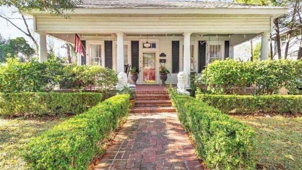 A two-story house with a central entrance, flanked by symmetrical hedges and a brick pathway leading to the front door. - Stylish Family 3BR Stay | Pets Allowed (Montgomery)