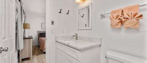 Une salle de bain moderne avec un meuble-lavabo blanc, des toilettes et un espace douche.