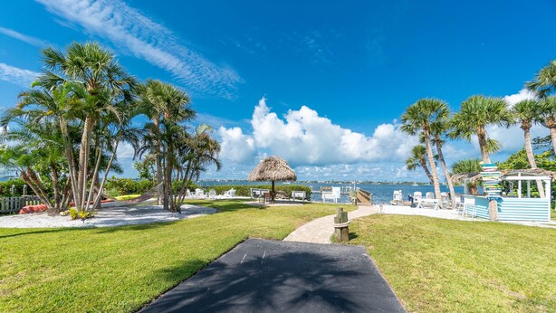 A tropical resort with a thatched-roof structure, palm trees, and a view of the sea.