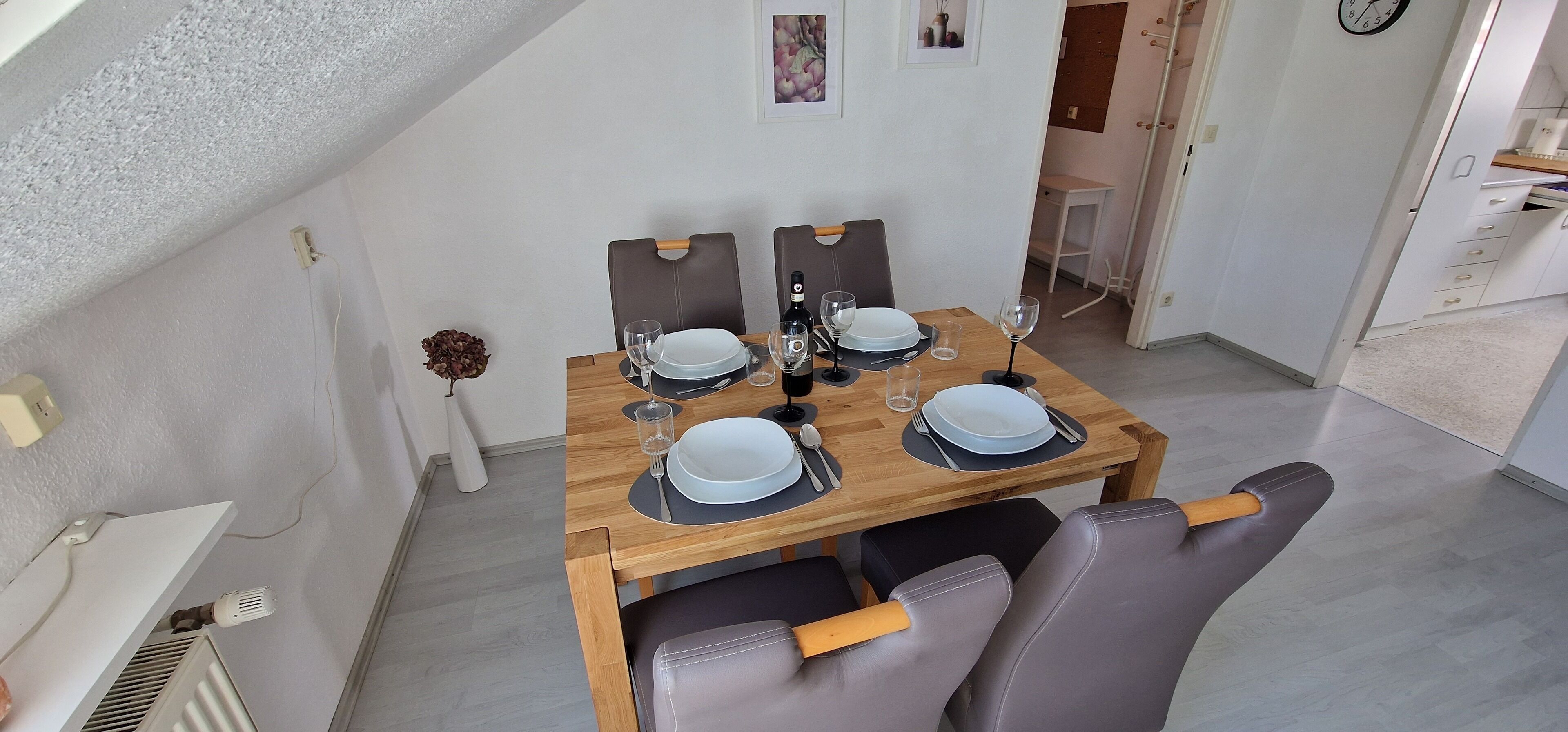 A dining area with a wooden table set for four, equipped with plates, glasses, and cutlery.