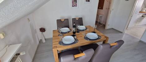 Un comedor con una mesa de madera dispuesta para cuatro personas, con platos, vasos y cubiertos.