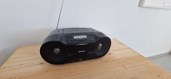 Un altavoz Sony negro sobre una mesa de madera frente a una pared lisa.