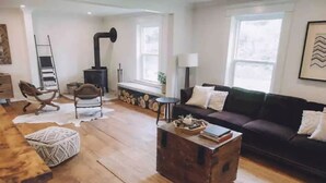 A cozy living room with a fireplace, a sofa, a coffee table, and a wooden floor. - 5 bdrm Farmhouse. Close to the beach. (Kensington)