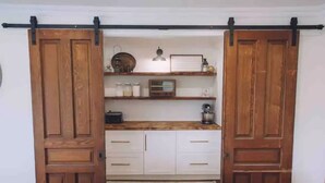A room with a wooden door, white cabinets, and a shelf with various items. - 5 bdrm Farmhouse. Close to the beach. (Kensington)