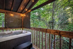 A wooden deck with a hot tub, surrounded by a wooden railing and a lattice wall.
