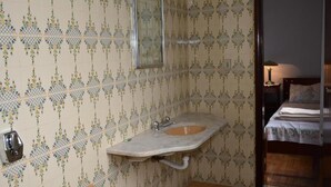 A bathroom with patterned wallpaper, a sink with a mirror, and a toilet. -  Pousada Barão Real (Sao Lourenco)