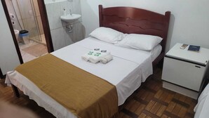A hotel room with a bed, a nightstand, a small refrigerator, a sink, and a shower area. -  Pousada Barão Real (Sao Lourenco)