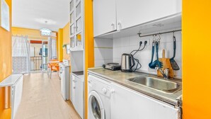Una cocina compacta con lavadora, hervidor y diferentes utensilios.