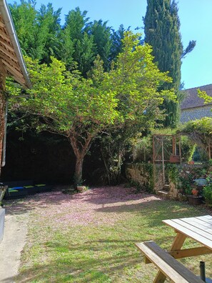 A garden with a wooden bench, a stone wall, and a variety of trees. - Gite les Glycines, 10 pers (+2bebes), 4bedroom, 2bathroom (Vicq-sur-Gartempe)