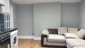 A modern living room with a washing machine, a sofa, and a wooden floor. - Barnet Luxury Apartment can sleep 4 people just few mins away from Station (Barnet)