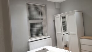 A bedroom with a bed, a wardrobe, a radiator, and a window with blinds. - Barnet Luxury Apartment can sleep 4 people just few mins away from Station (Barnet)