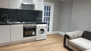 A modern kitchen with white cabinets, a built-in oven, a washing machine, and a black countertop. - Barnet Luxury Apartment can sleep 4 people just few mins away from Station (Barnet)