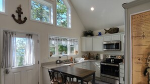 A kitchen with a large island, white cabinets, and a view of trees through the windows.