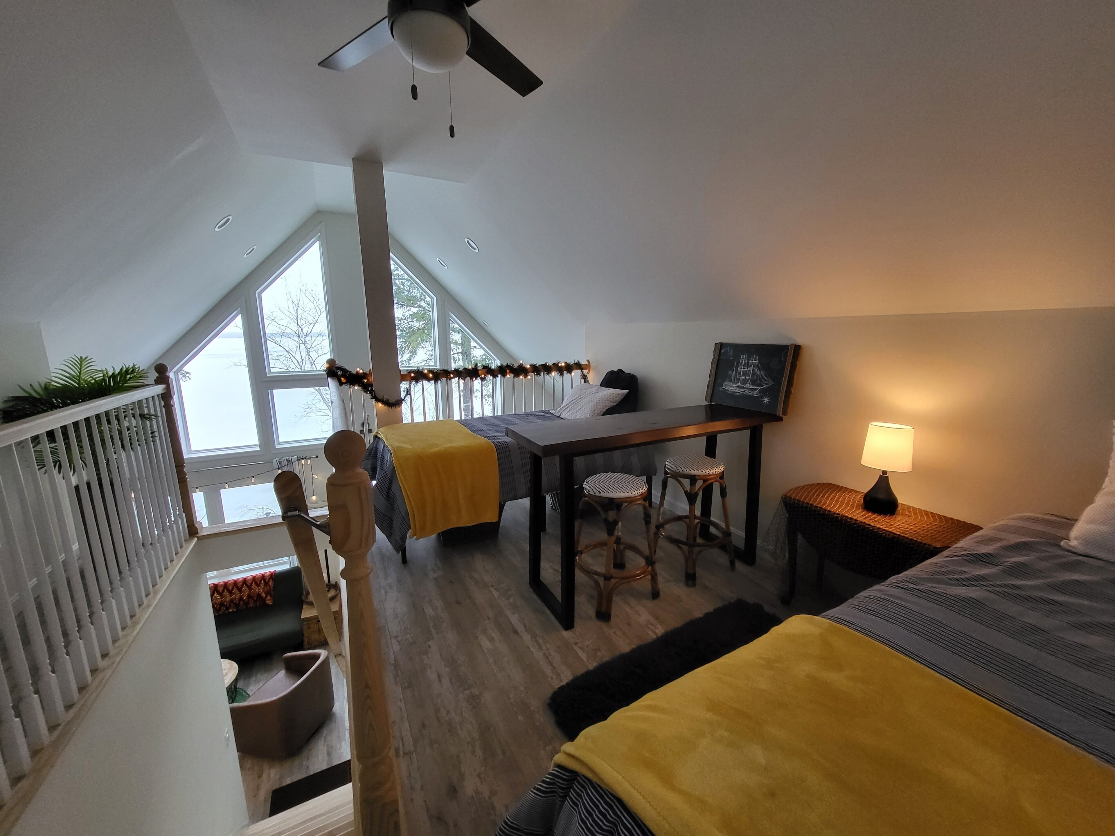 A bedroom with a bed, a desk, two chairs, a lamp, and a window.