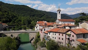 Eine historische Stadt mit einem Fluss, einer Brücke und einem Kirchturm.