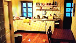Eine Küche mit Fenster, Spüle und einer Essecke mit einem Stuhl.