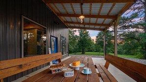 A wooden table with benches, a sign reading "BUTTER", and a window with a blue door. - Hidden Hills Hideaway- Broken Bow/Hochatown- 2bd (Smithville)