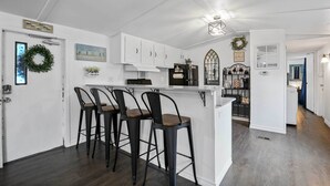 A kitchen with white cabinets, a bar area with stools, and a dining area with a chandelier. - Near Water: Lake Dallas Home w/ Furnished Patio! (Lake Dallas)