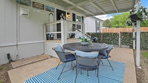 A covered patio with a round table and chairs, a welcome sign, and a view of the backyard. - Near Water: Lake Dallas Home w/ Furnished Patio! (Lake Dallas)