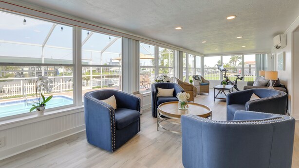 Una luminosa sala de estar amplia con grandes ventanales, vista a la piscina y muebles modernos.