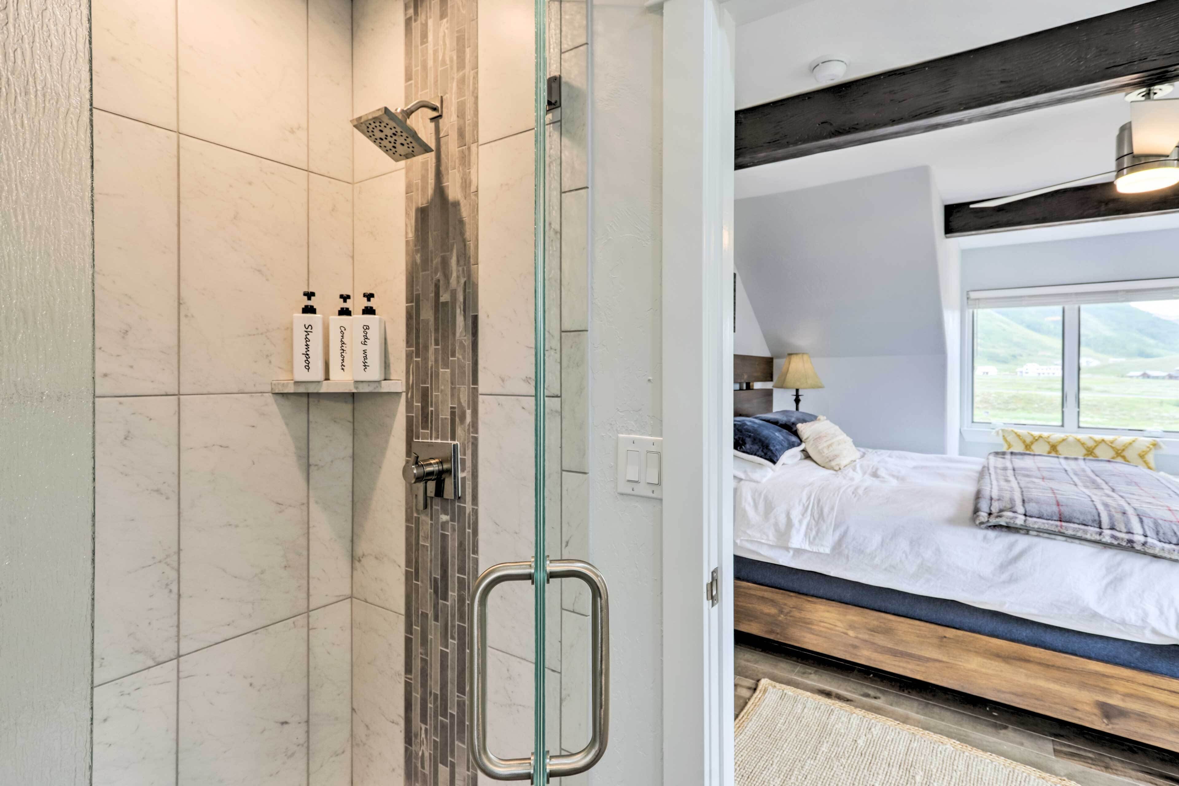 Une salle de bain moderne avec une douche à parois de verre, un lavabo blanc et des articles de toilette.