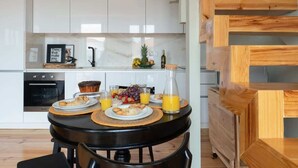 A modern kitchen with white cabinets, a black dining table, and a wooden staircase. - Modern Design Duplex w/ Balcony by HostWise (Porto)