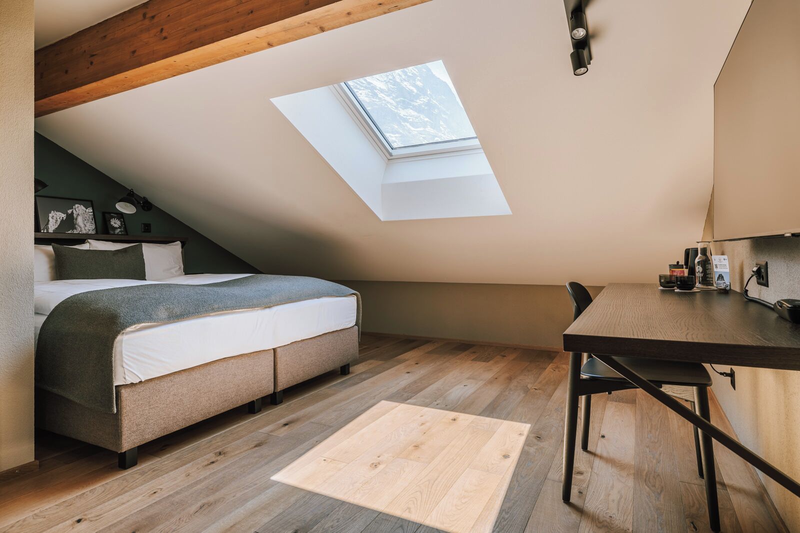Um quarto de sótão aconchegante com um claraboia, uma cama, uma escrivaninha e uma mesinha.