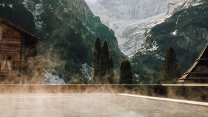 A mountain cabin with a hot spring, surrounded by snow-covered peaks and evergreen trees. - Hotel Fiescherblick (Grindelwald)
