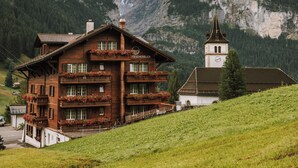 A wooden chalet with balconies, a church, and a mountain backdrop. - Hotel Fiescherblick (Grindelwald)