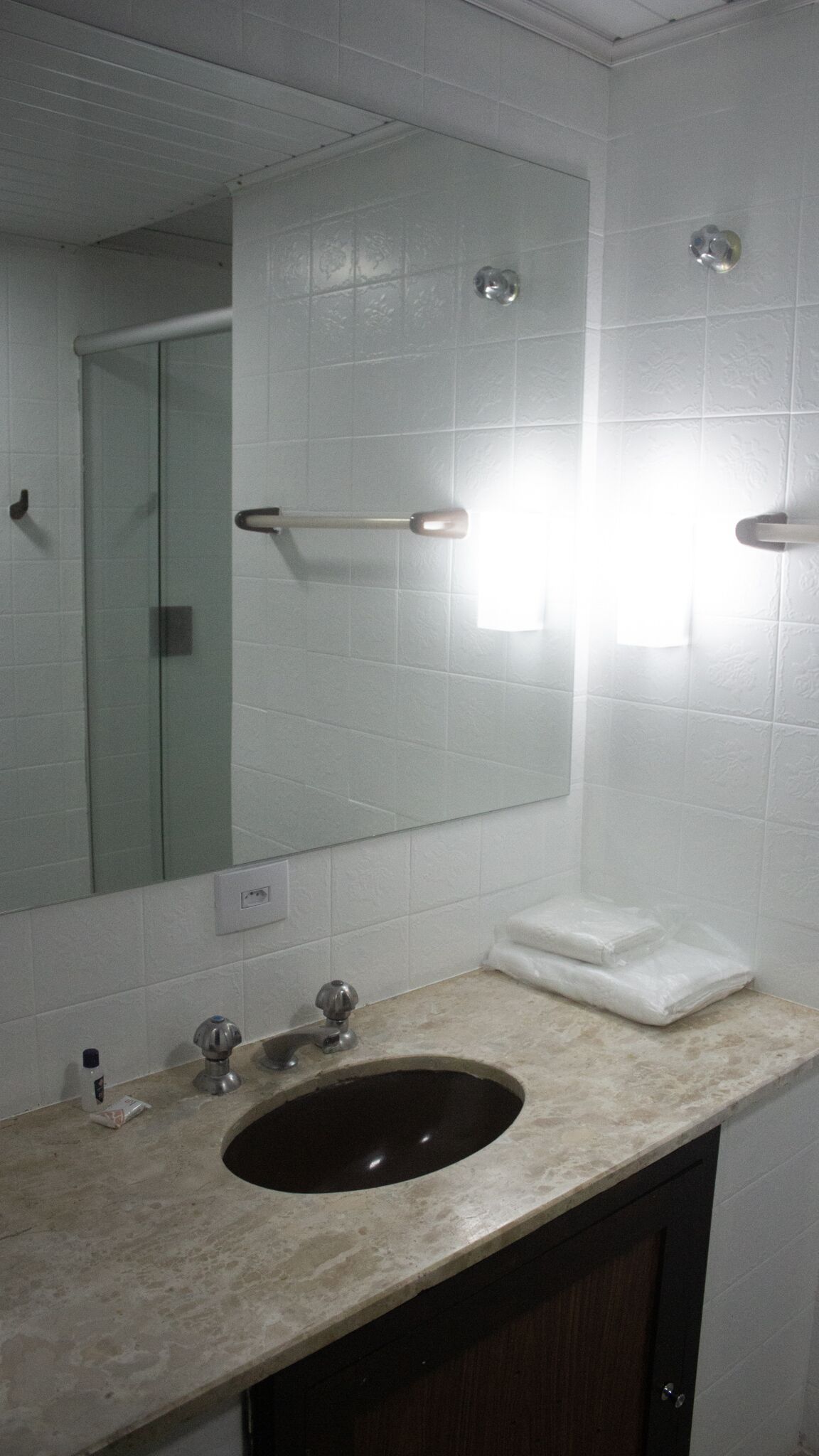 A bathroom with a large mirror, a sink with a dark basin, and a towel rack.
