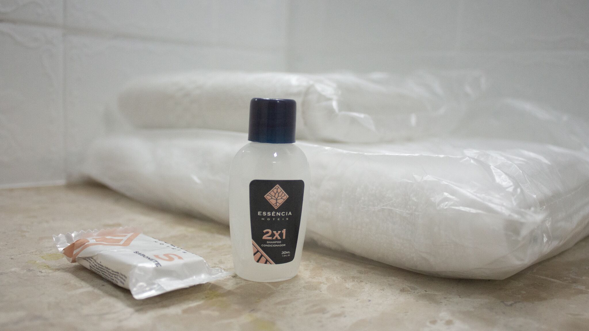 A bathroom with a white bathtub, a bottle of shampoo, and a packet of soap.