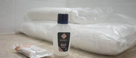 A bathroom with a white bathtub, a bottle of shampoo, and a packet of soap.