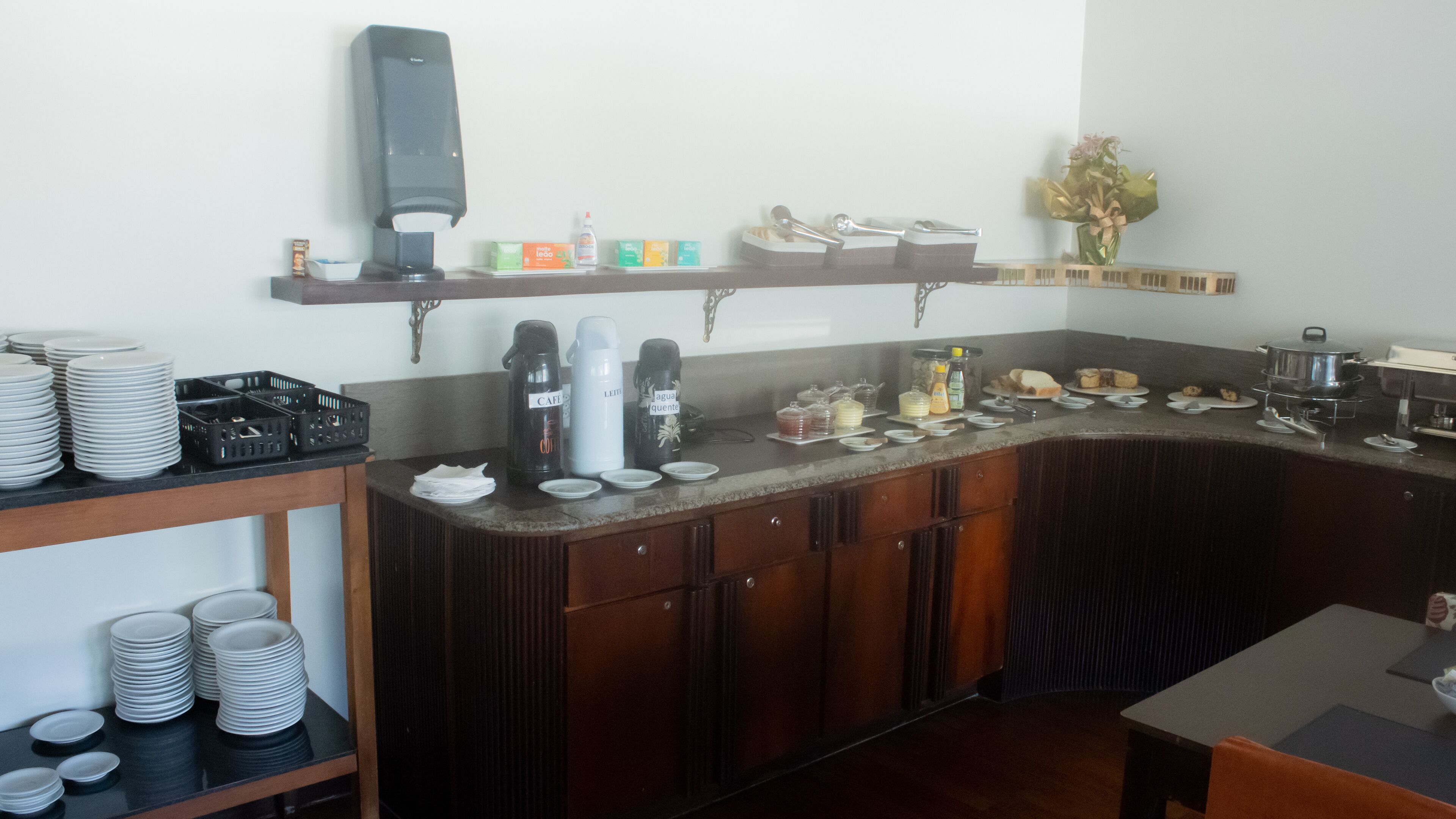 A buffet setup with plates, cups, and condiments.