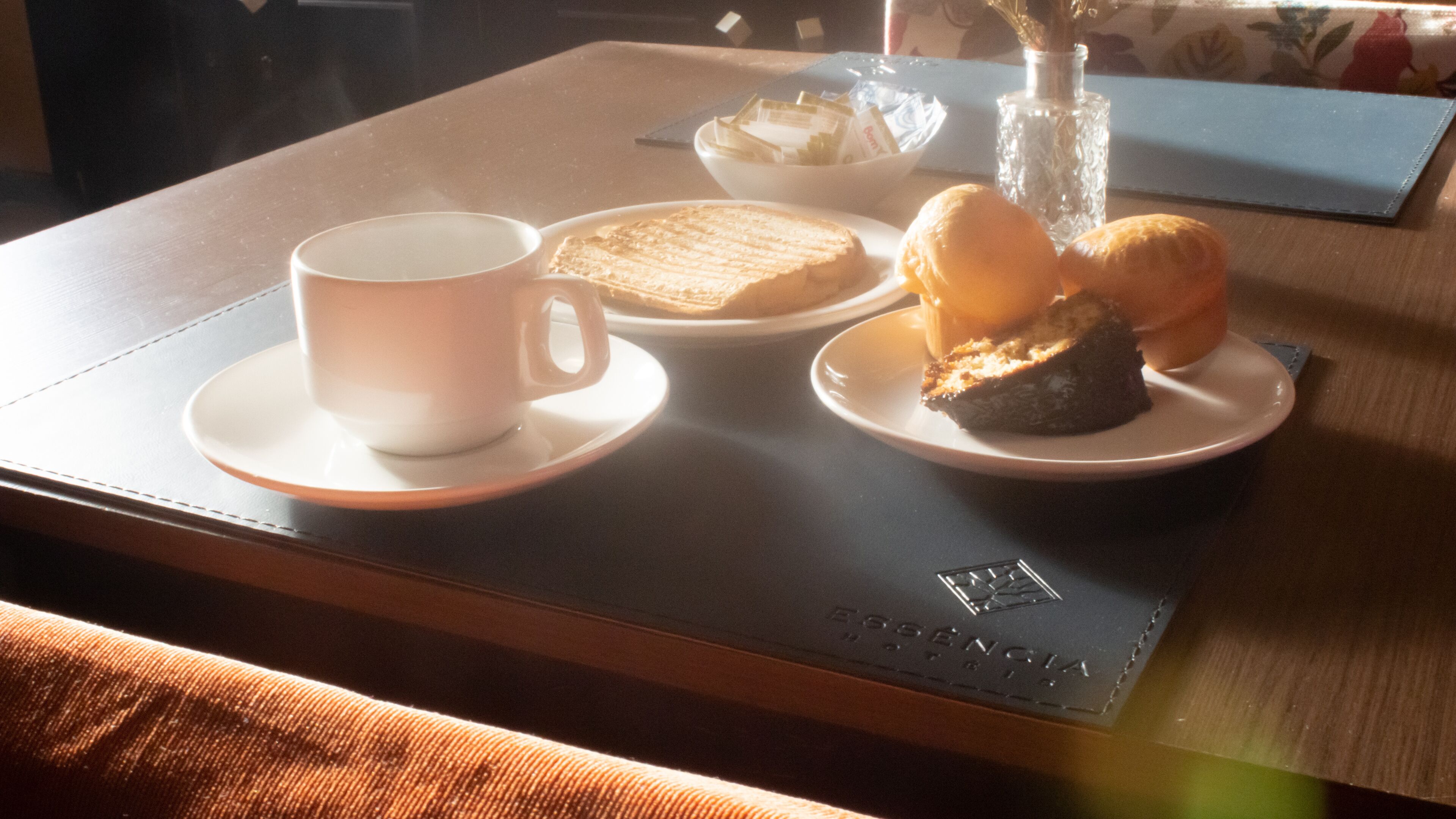 Una mesa con una taza, un plato de tostadas y un plato de pasteles.