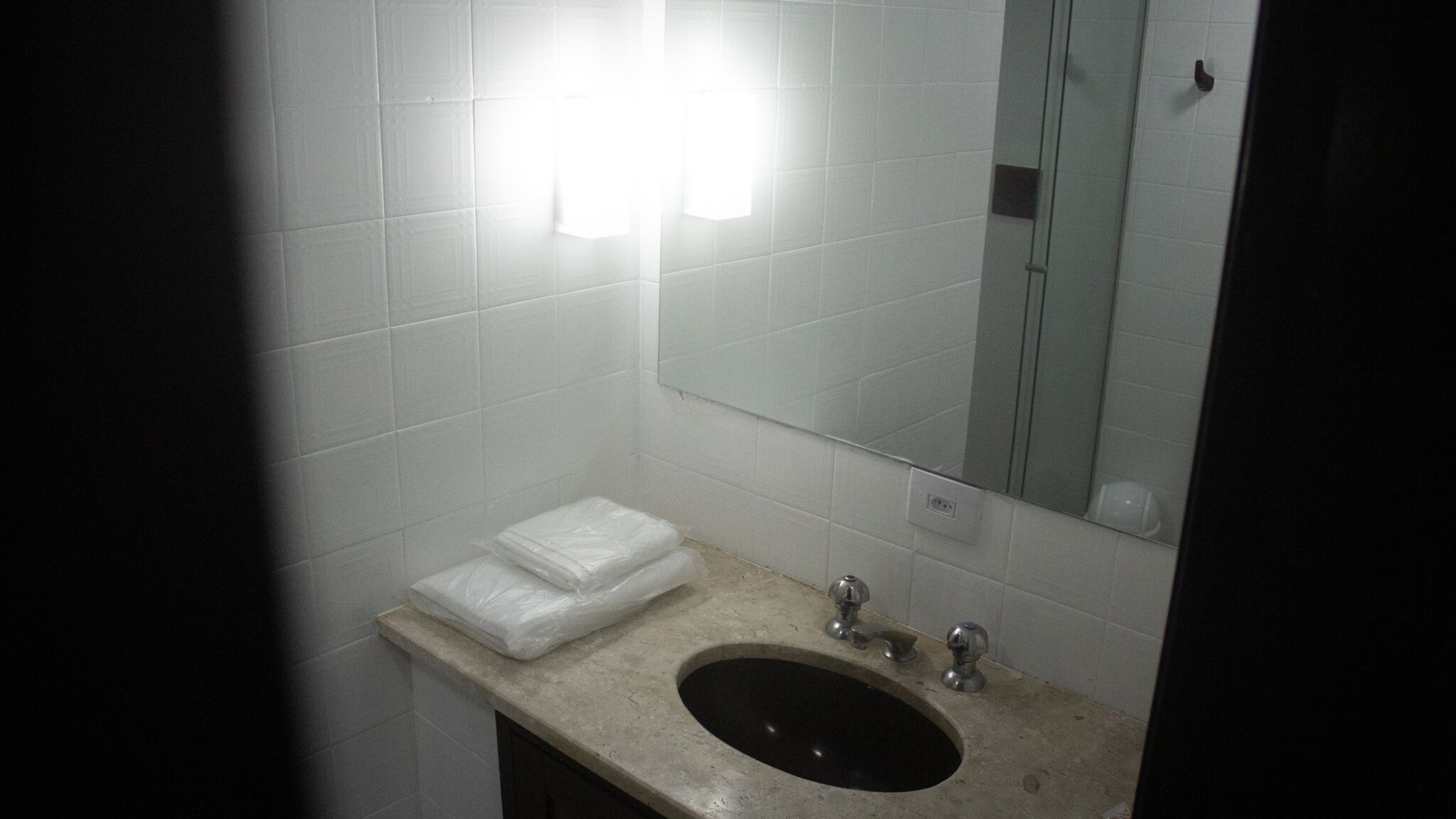 A bathroom with a sink, mirror, and white tiles.