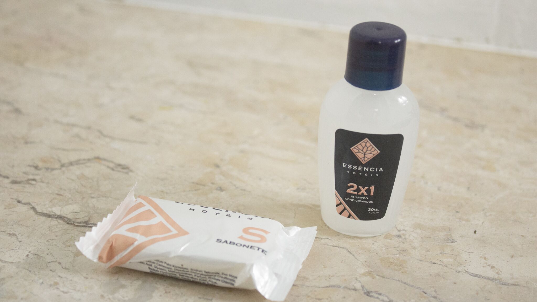 Eine Flasche ESSENCIA-Shampoo und eine Seife auf einer Marmorplatte.