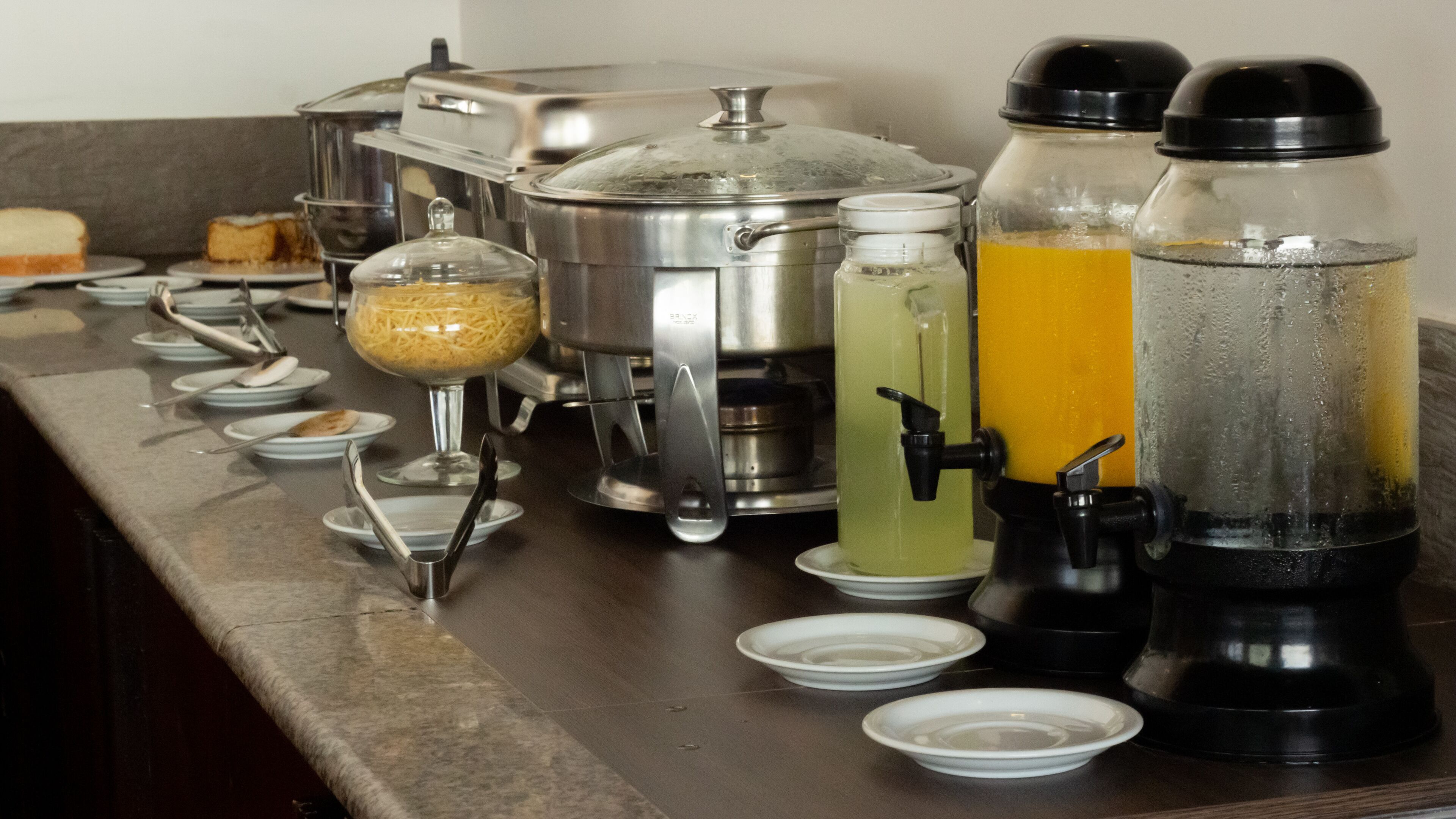 Montaje de bufé con diversos alimentos, una máquina de café y dispensadores de bebidas.