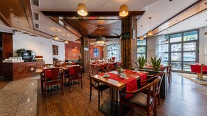 Een restaurant met houten tafels en stoelen, een koffieapparaat en grote ramen.
