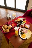 A breakfast table with bread, pastries, fruit, eggs, and beverages.