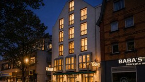 Een hotel met een moderne gevel, meerdere ramen en een bord met de vermelding dat het een hotel is.