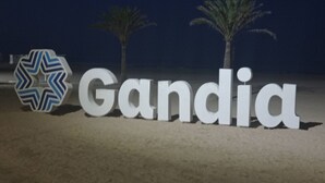 Een bord met de tekst 'Gandia' en een logo met een blauw-wit chevrondessin.