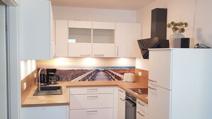 A compact kitchen with white cabinets, a wooden countertop, a built-in oven, and a coffee maker. - Modern top floor apartment with a view of the sea and Stralsund (Altefähr)