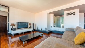 Ein modernes Wohnzimmer mit Flachbildfernseher, einer Couch, einem Couchtisch und einem Konsolentisch mit Dekorationselementen.