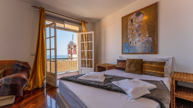 Ein Hotelzimmer mit einem großen Bett, Blick auf ein Glockentürme und einem Gemälde an der Wand.