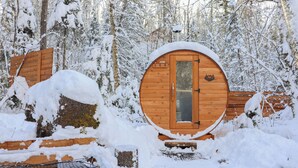 Una cabaña de madera con una puerta circular, rodeada de árboles cubiertos de nieve.