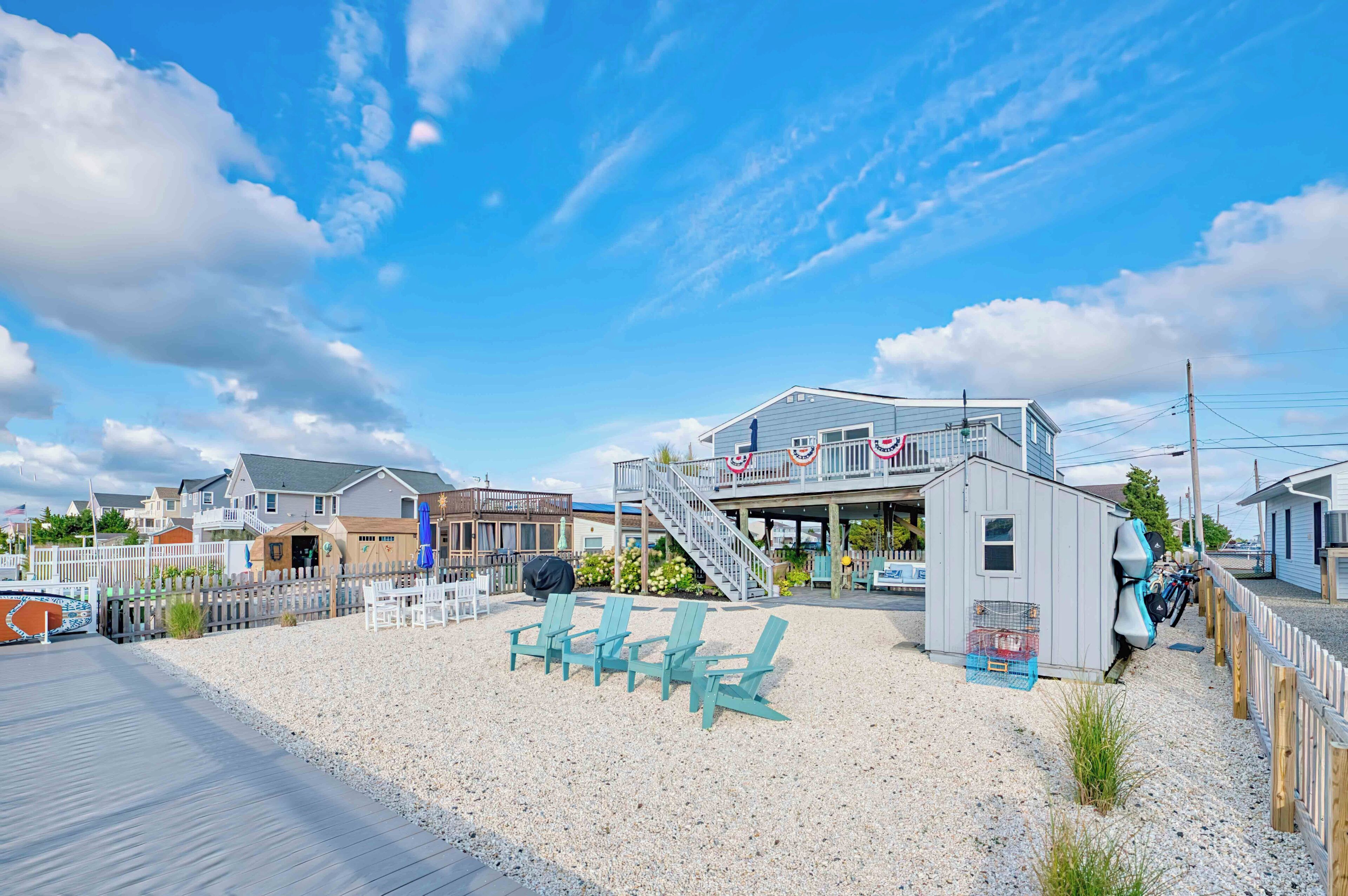 Una propiedad frente a la playa con un muelle de madera, asientos al aire libre y un edificio con una escalera que lleva a un deck.