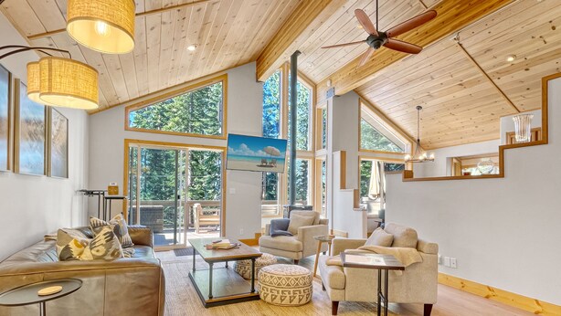 A spacious living room with a high ceiling, large windows, and a ceiling fan. - Lake Views, Hot Tub, Walk to Beach! (Carnelian Bay)