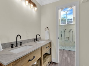 A bathroom with a double sink, wooden vanity, and a glass shower enclosure.