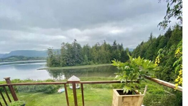 Un jacuzzi en una terraza de madera con vistas a un lago y un bosque.